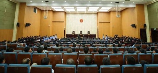 People standing in a courtroom, with a mix of defendants and police officers.